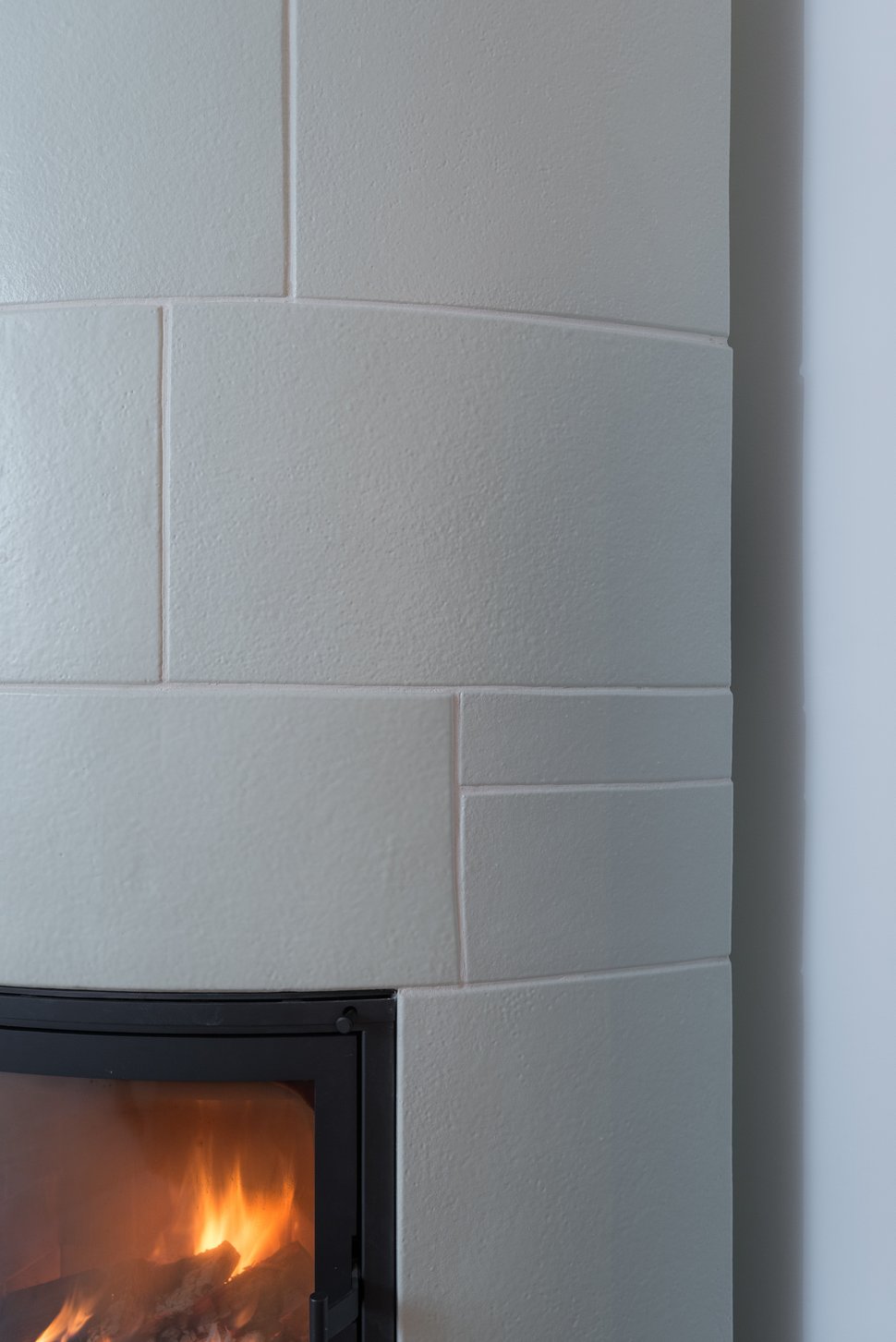 Close-up of a white tiled stove with a black firebox.