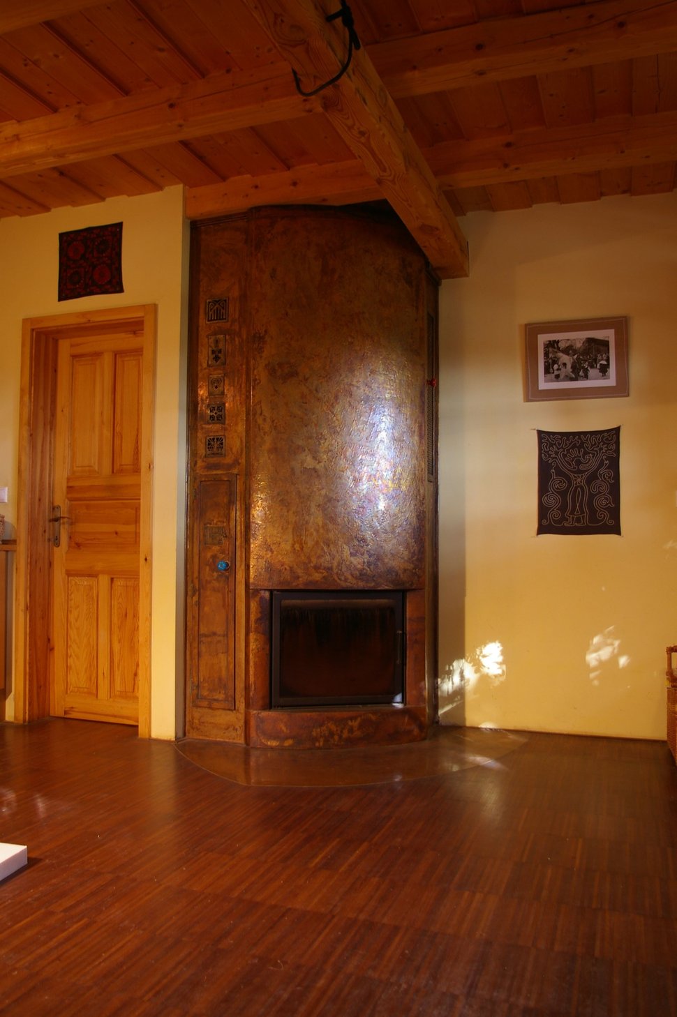 A copper-clad stove wall in a wood-panelled room, with a dark firebox.