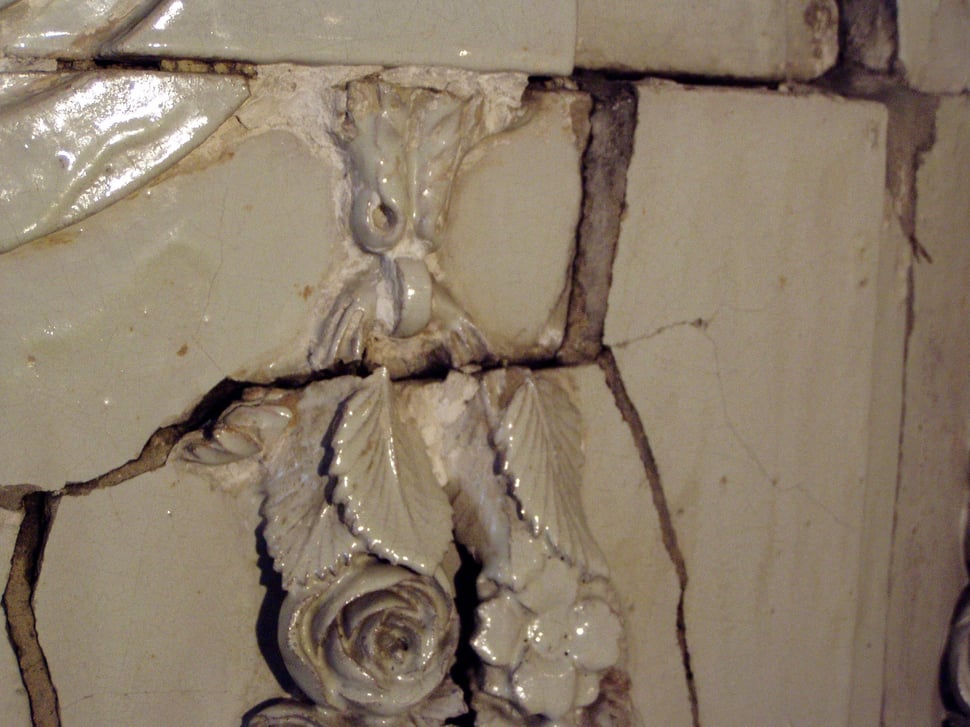 Cracked white relief tiles with scroll and leaf motifs.