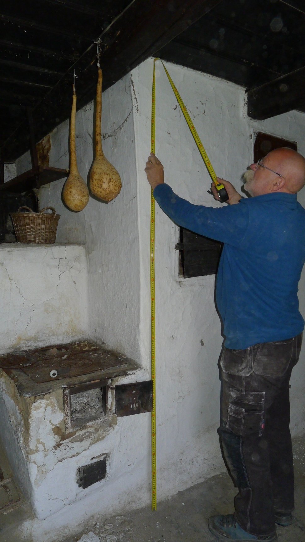 A man measuring a white stove wall with a yellow tape measure.