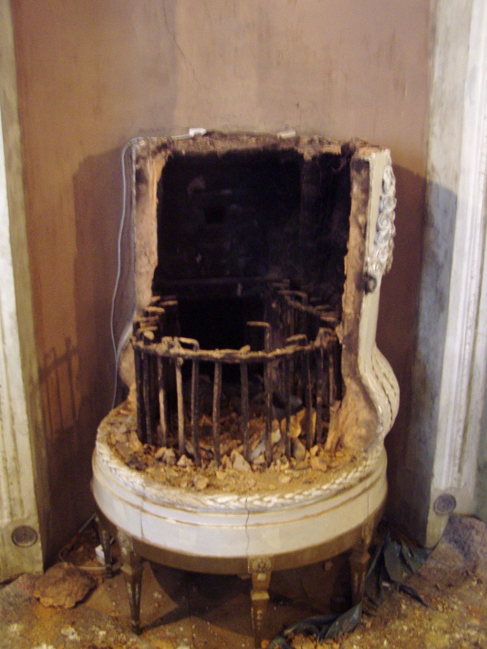 The open firebox of an old stove, blackened and filled with an iron grate.