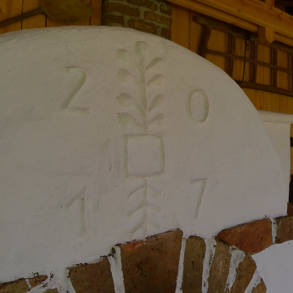 Plaster relief with the year 2017 and a plant motif above brickwork.