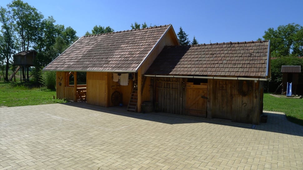 The wooden house from the main house, across a paved yard.