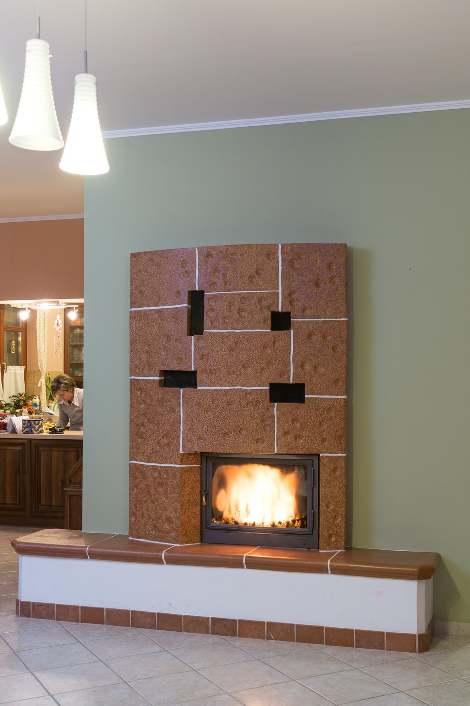 The lit stove beneath pendant lights in a pale green room.