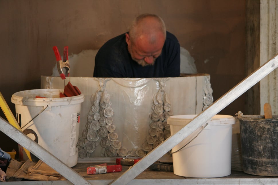 A man working on white stove ornaments in a workshop.
