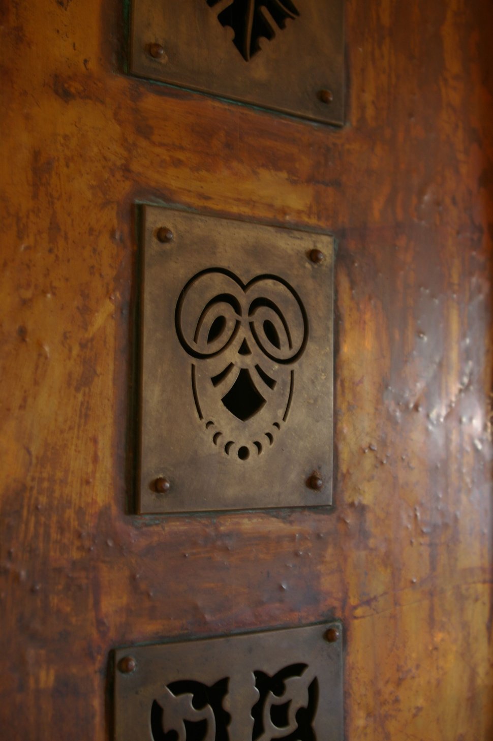 Three cast-iron decorative plates fixed to a copper door.