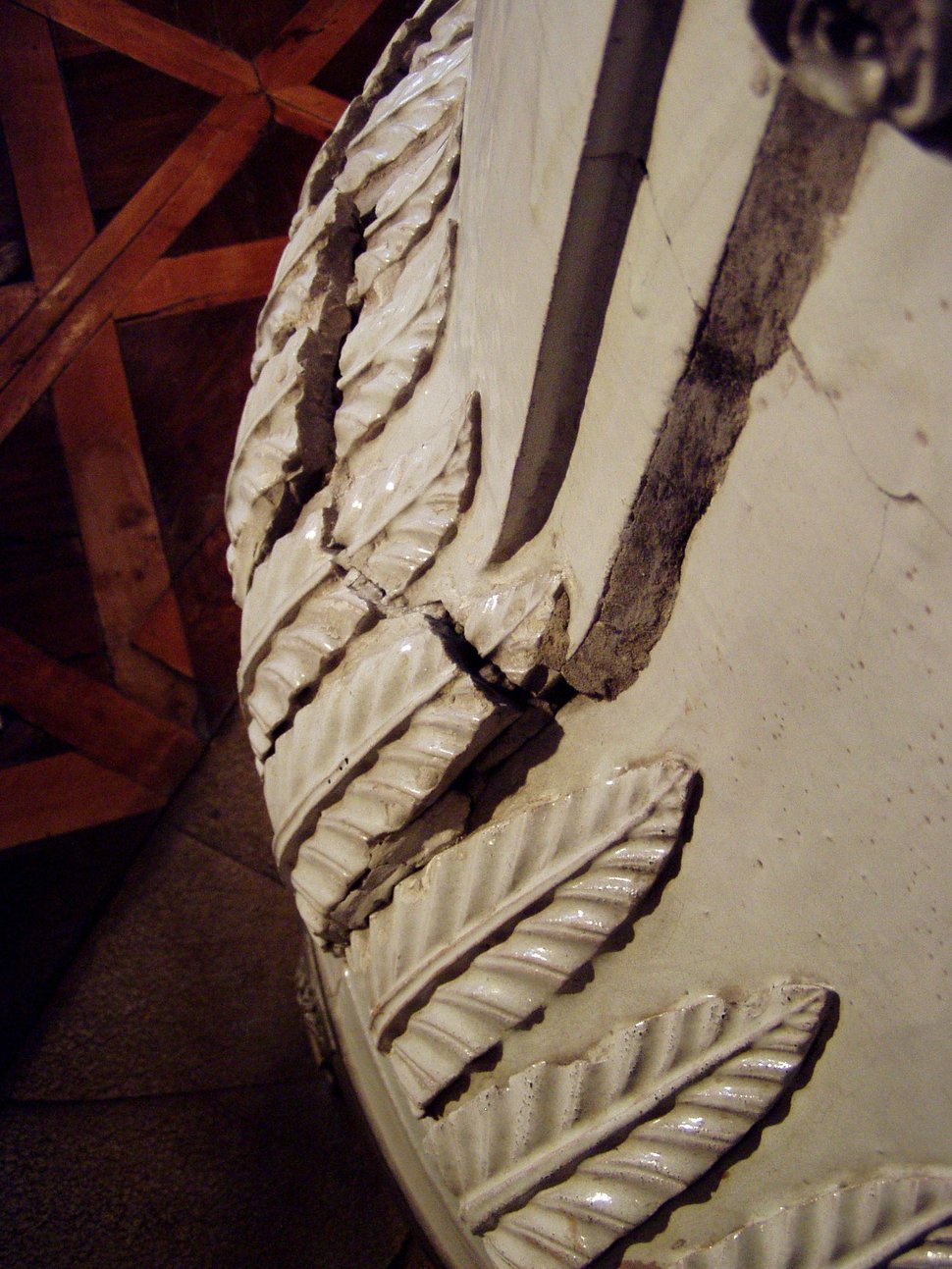 A carved white ornament on an old stove, with rope-like details.