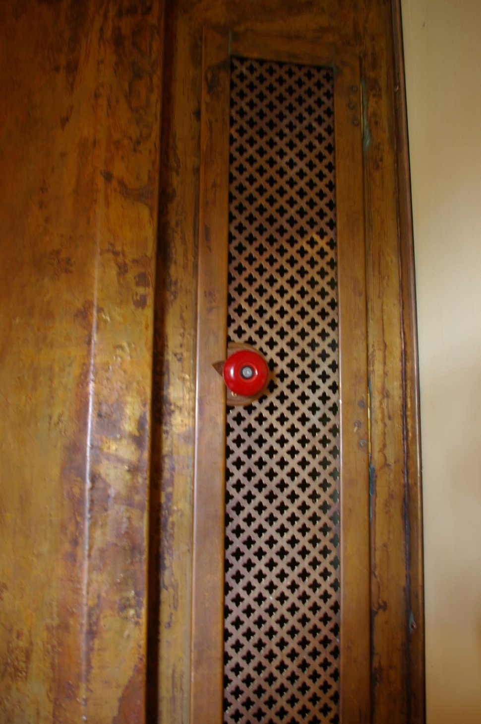 A tall copper surface with a narrow lattice vent and a red circular knob.