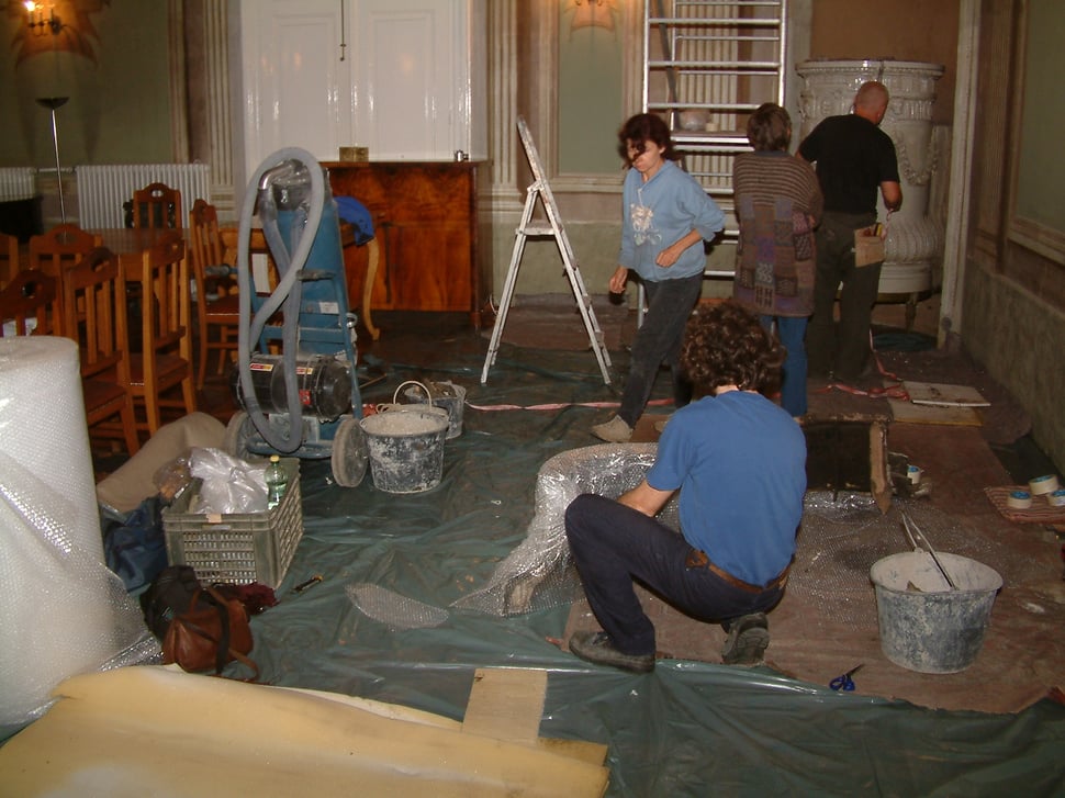 A workshop floor with people wrapping large white stove sections.