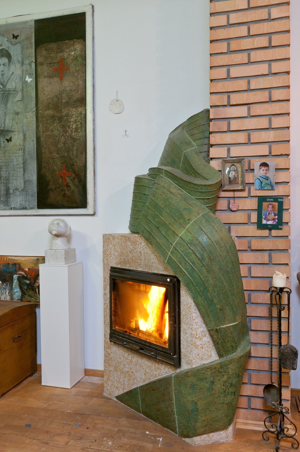 The green stove against exposed brickwork, with paintings behind.
