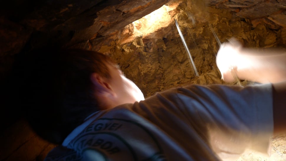 A child inside a tunnel-like oven, one arm reaching out.