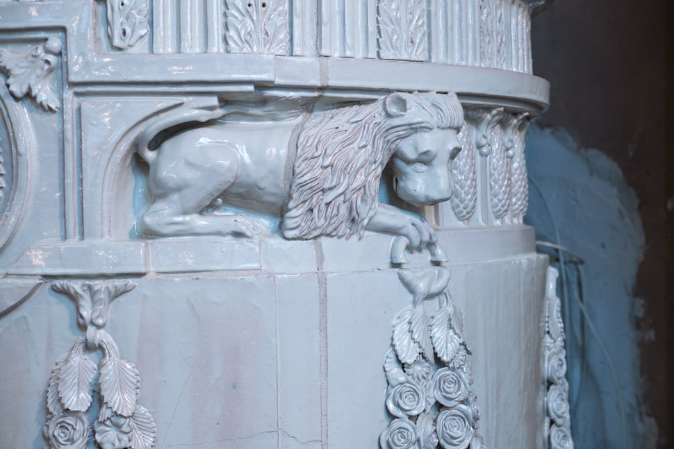 A carved white lion relief on the side of an ornate palace stove.