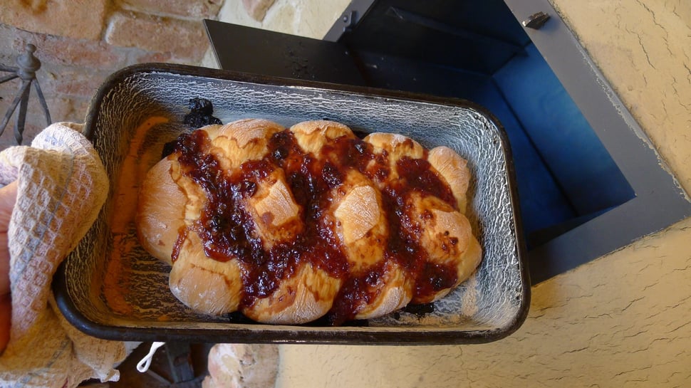A tray of jam-topped buns resting on a stone ledge.