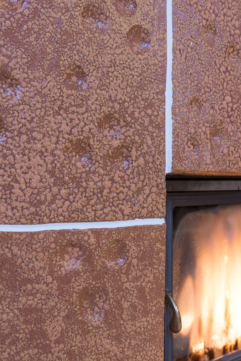 Brown glazed tiles beside a firebox with visible flames.