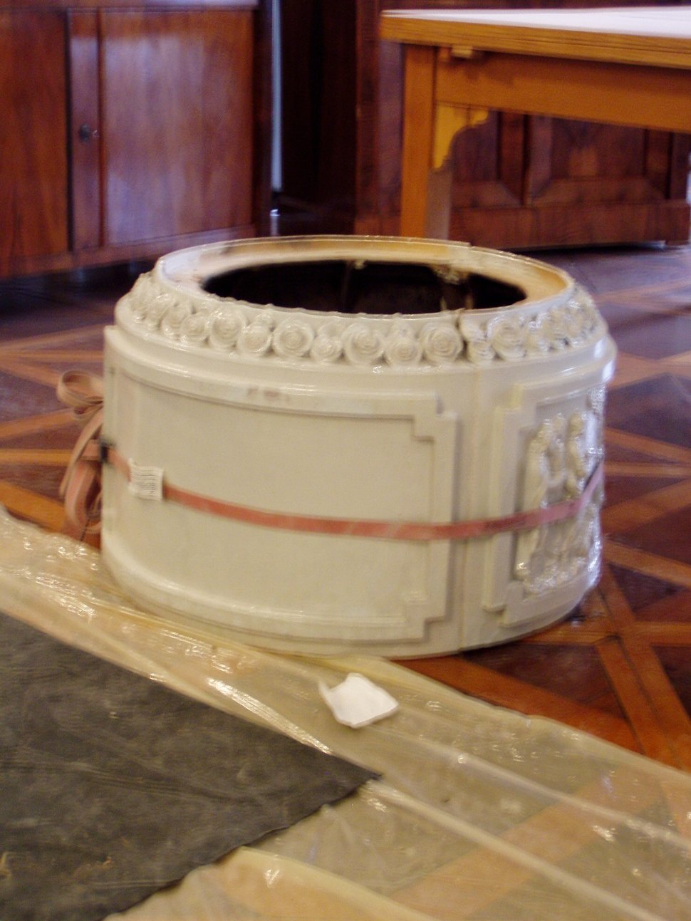 A round white stove section resting on a pallet.