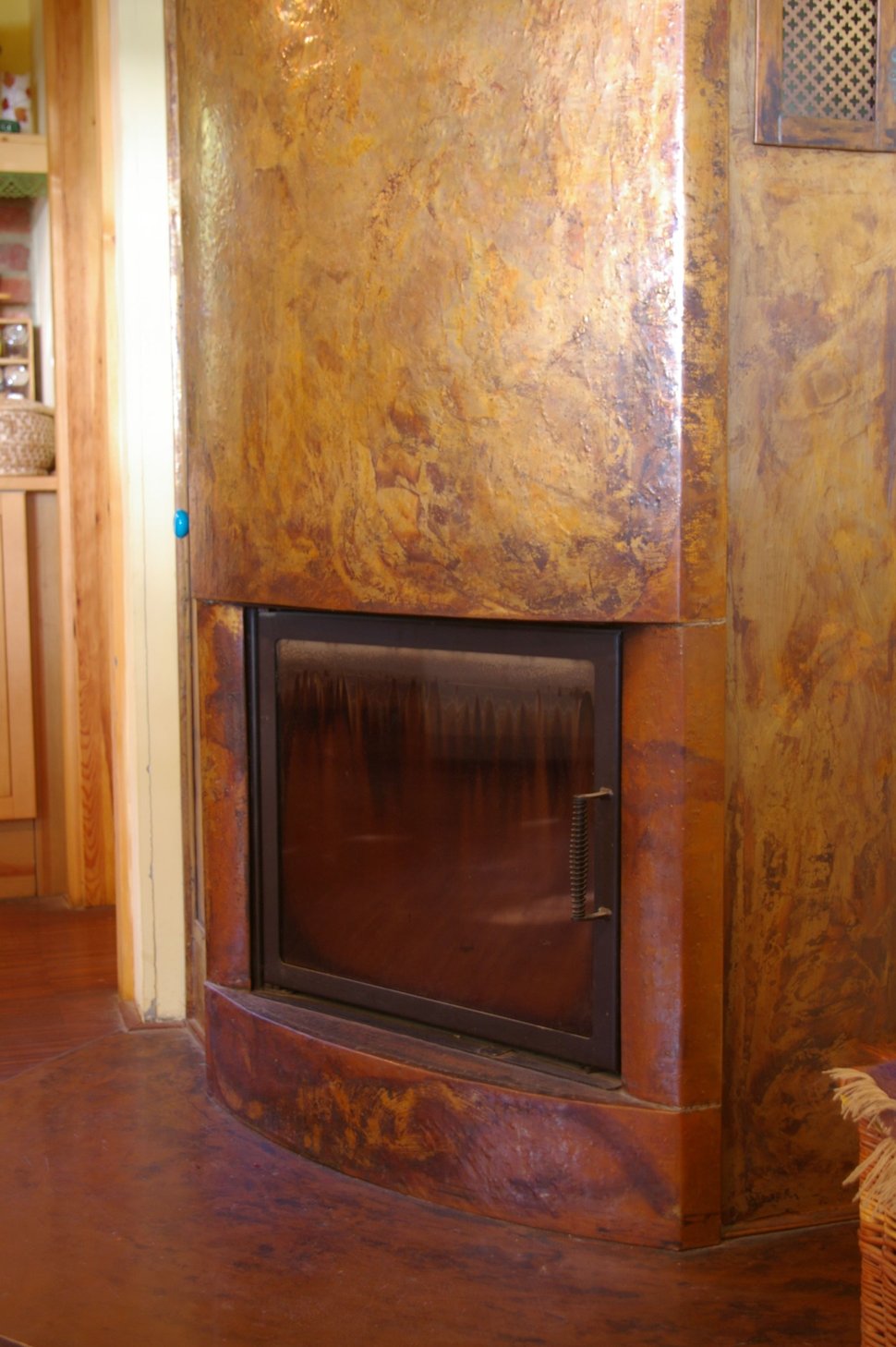 A copper wall above a curved hearth, with the firebox glowing.