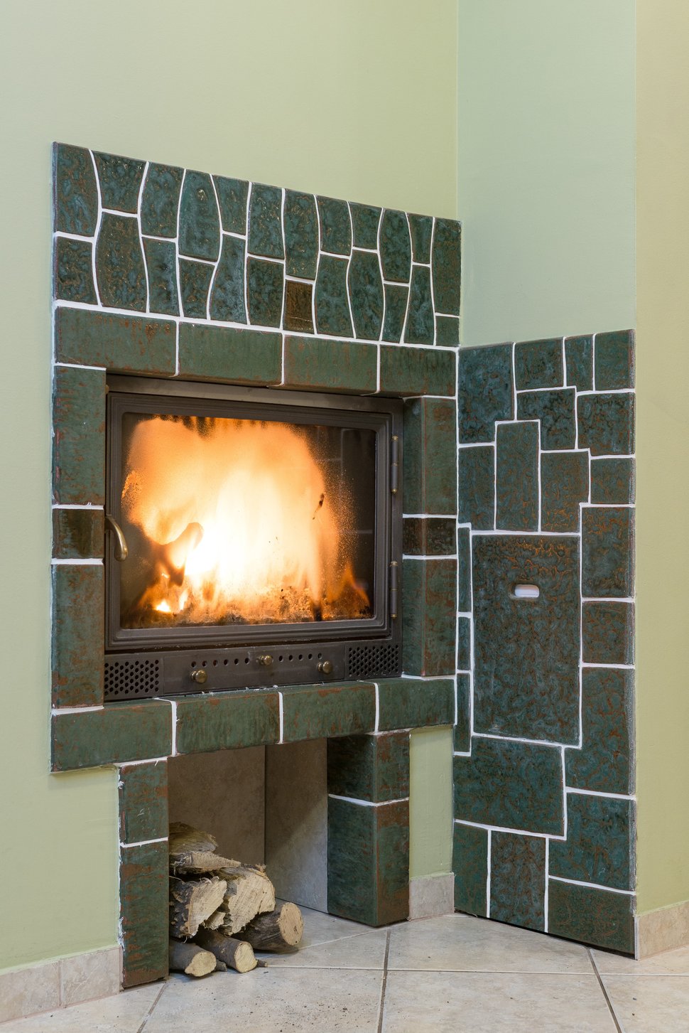 Green stone tiles around the stove firebox, with a wood store below.