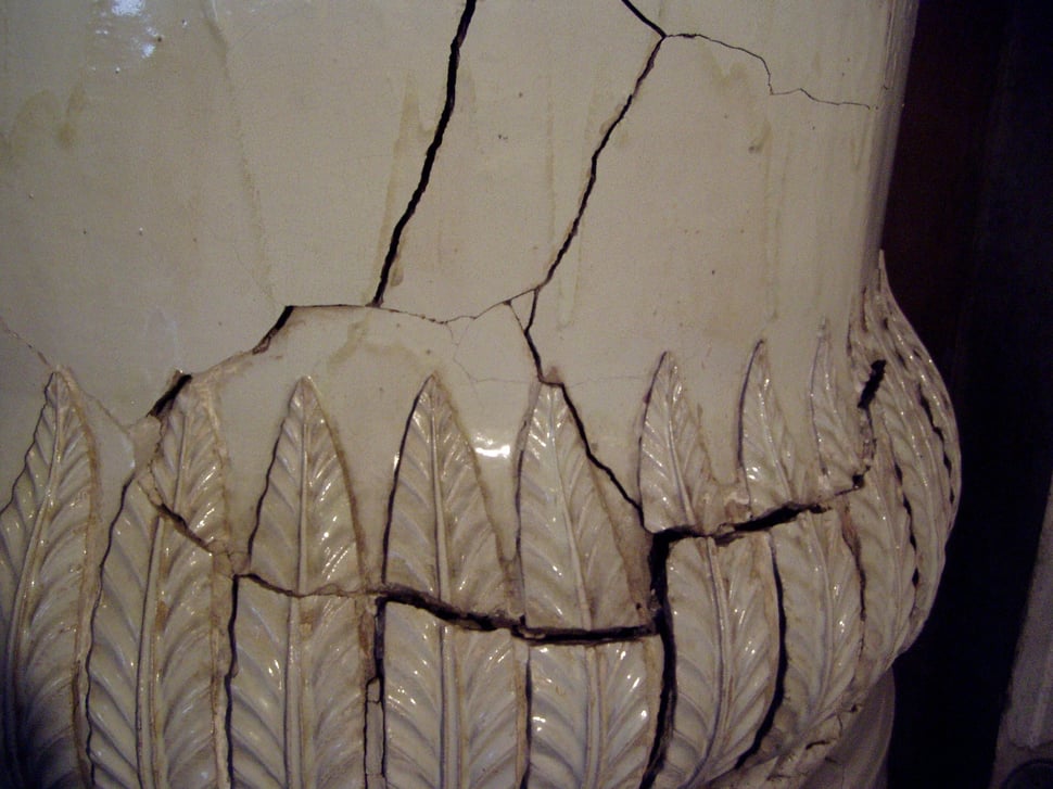 Cracked cream stove tiles with a carved leaf relief.