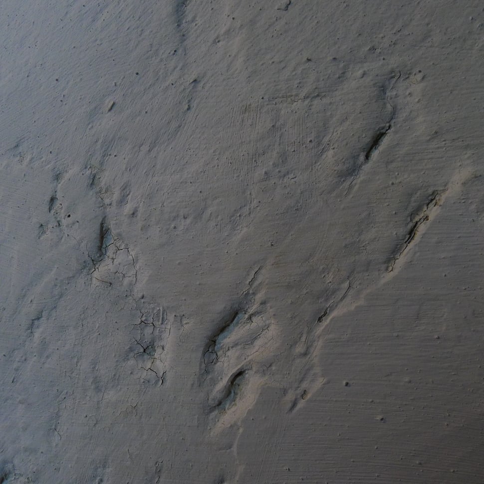 Close-up of a rough grey clay and plaster surface.