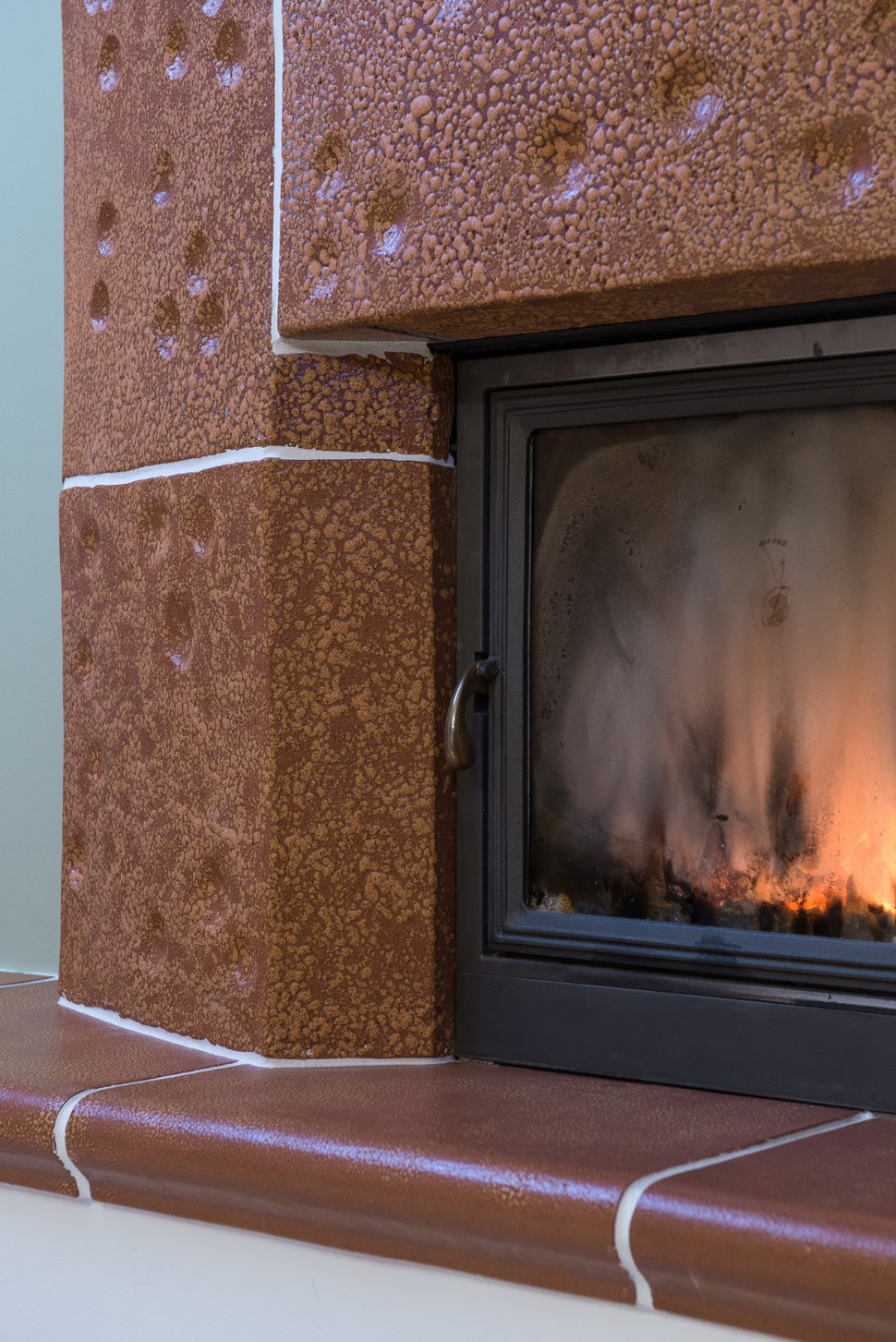 A close-up of flames inside the black firebox, framed by brown tiles.