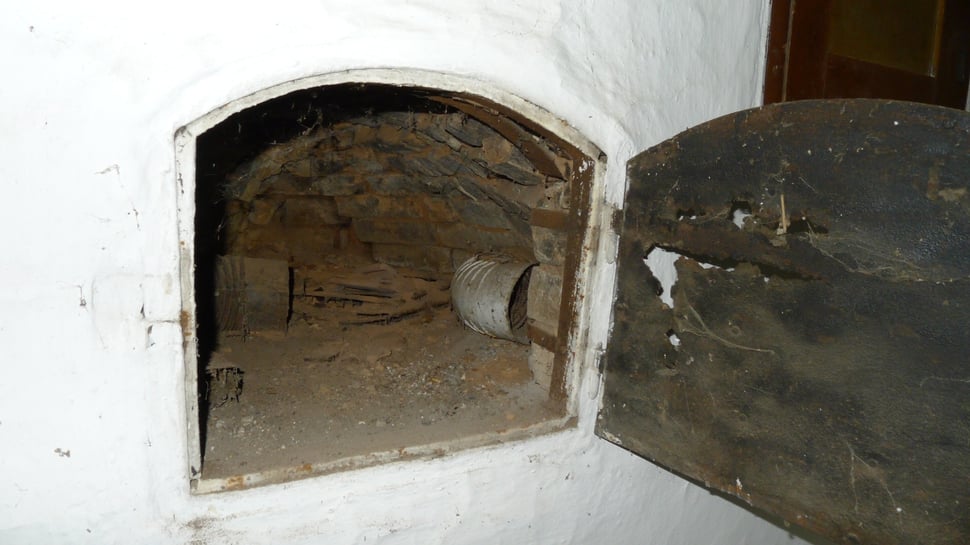 An open black oven door revealing a brick-lined interior.