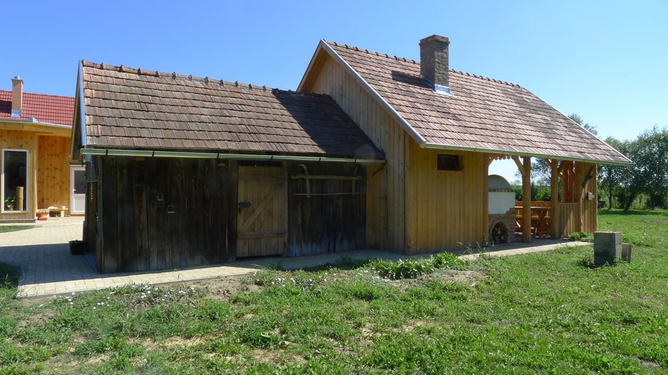 A new wooden house with a tiled roof, chimney and covered porch.