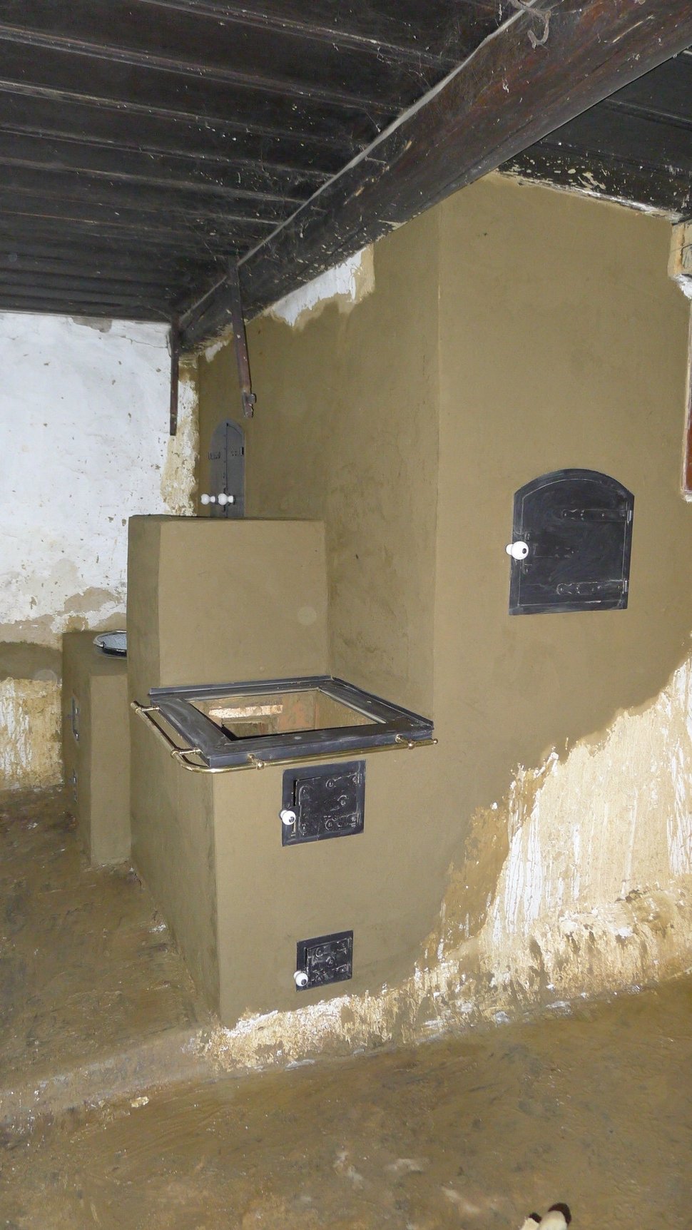 A beige stove in an unfinished room with a rough wall.