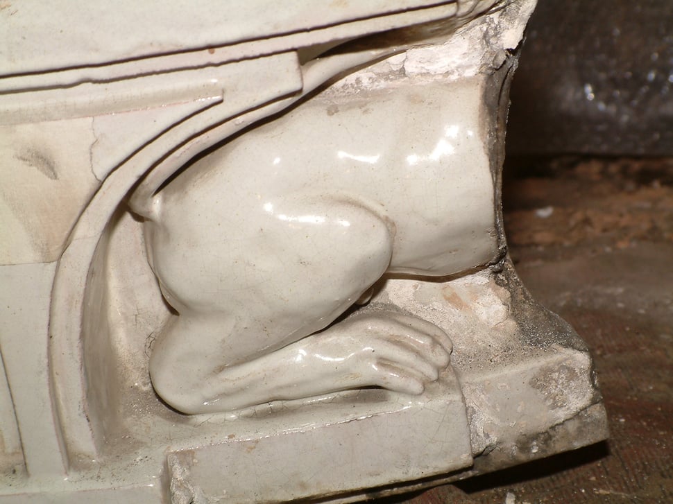 The back of a white lion relief on the stove, with carved details.