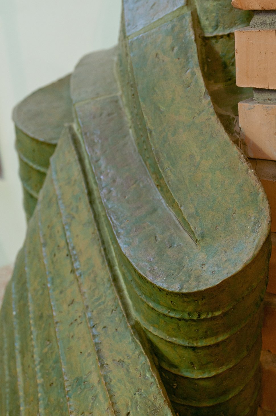 Close-up of the green stove's overlapping, leaf-like tile edges.