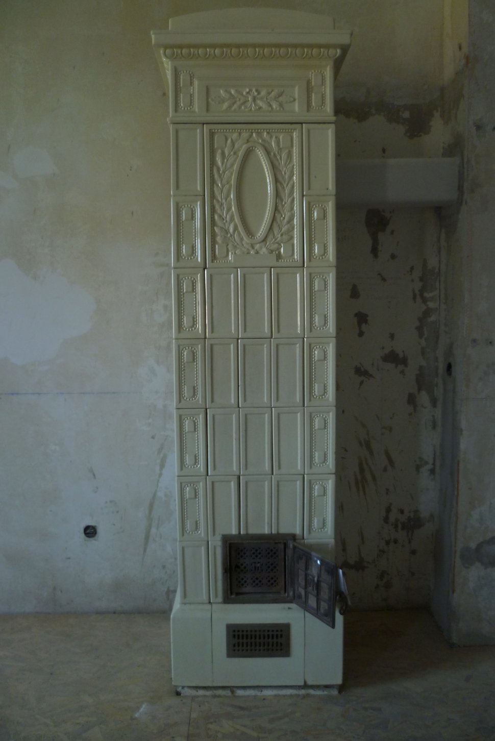 The rebuilt stove standing in its new place against a bare wall.
