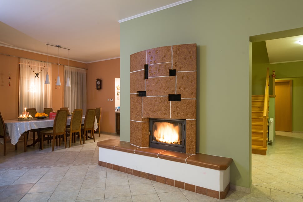 The stove seen across a dining room, with stairs and a hallway beyond.