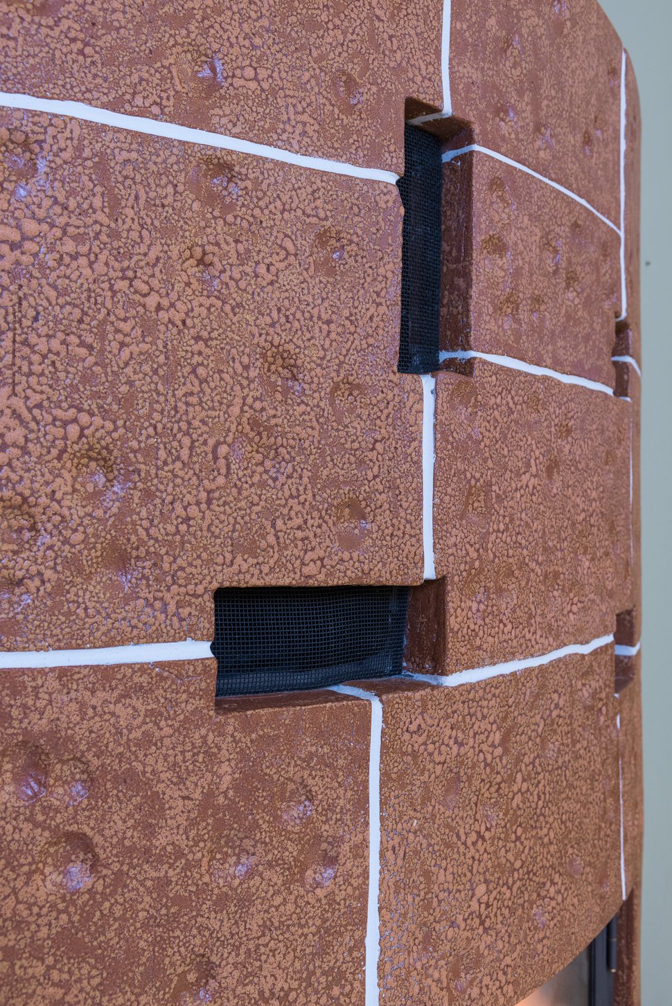 Brown glazed tiles with white grout around two black handles.
